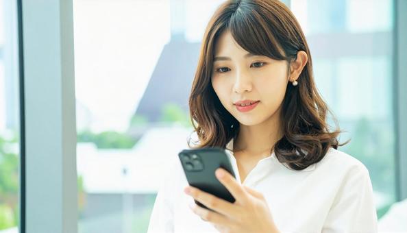 スマホを確認するビジネス女性 スマホを確認するビジネス女性の写真
