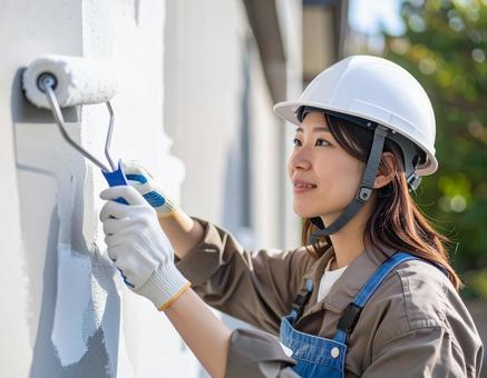 DIYで外壁塗装する女性の写真
