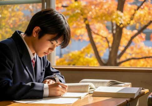 秋の教室で勉強に集中する男子学生の写真