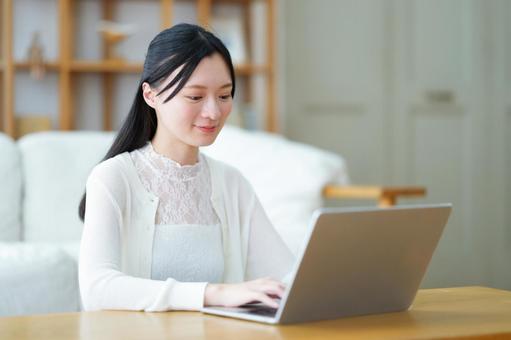 微笑みパソコン作業中の白い服の女性 女性,ノートパソコン,座るの写真素材