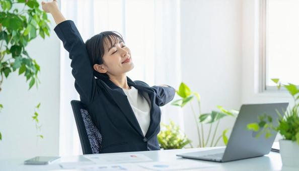 仕事が終わり達成感で背伸びをする社員 仕事が終わり達成感で背伸びをする社員の写真
