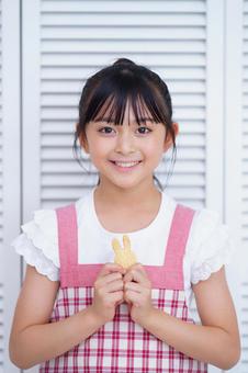 手作りクッキーを嬉しそうに見せるエプロン姿の少女 女の子,クッキー,持つの写真素材
