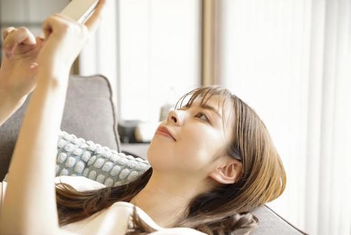 A young woman relaxing and enjoying her smartphone, JPG