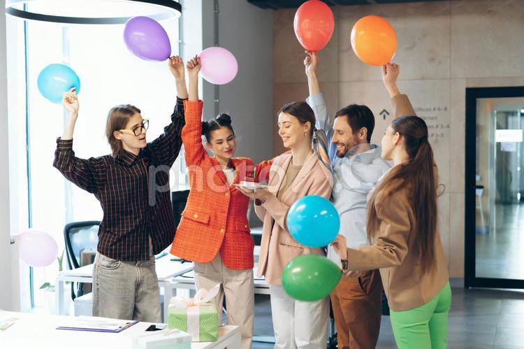 オフィスでみんなで風船を持って女性の誕生日を祝っている同僚 ビジネス,ビジネスマン,ビジネスウーマンの写真素材