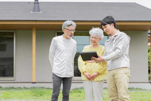住宅の前で説明する男性作業員とシニア夫婦 住宅の前で説明する男性作業員とシニア夫婦 シニア,夫婦,リフォームの写真素材