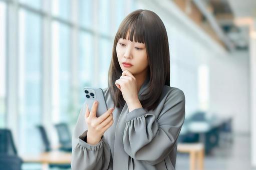 スマホを見て考える女性・ビジネスウーマン 女性,困る,考えるの写真素材