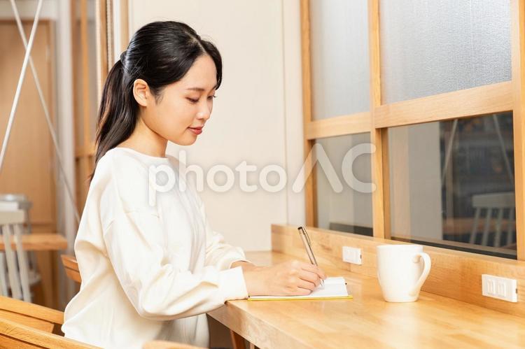 カフェでメモをするアジア人女性01 女性,メモ,考えるの写真素材