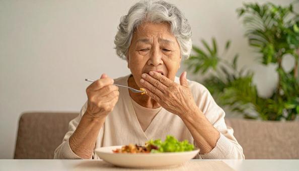 食事中、歯が痛む高齢者女性 食事中、歯が痛む高齢者女性の写真