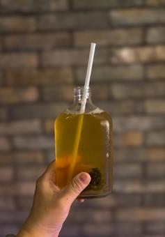 冷たい緑茶ドリンクを持つ手とレンガ背景 緑茶,飲み物,ドリンクの写真素材