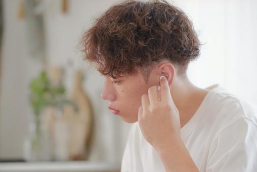 ワイヤレスイヤホンをつける若い男性 ワイヤレスイヤホンをつける若い男性 イヤホン,ワイヤレスイヤホン,音楽の写真素材
