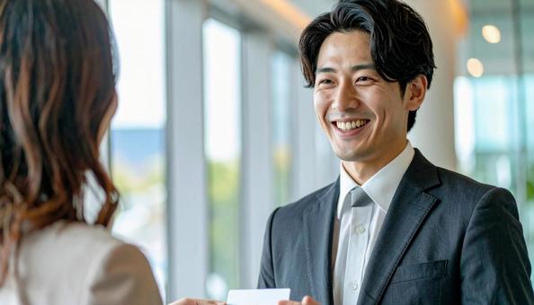 笑顔で名刺を差し出す男性社員の写真