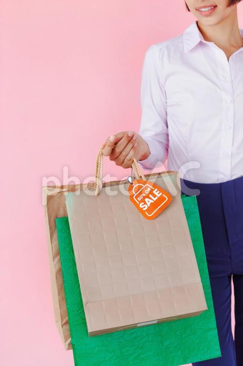セールで買った物が入ったたくさんの紙袋を持つ女性（ピンク背景　顔なし） セール,ショップ,女性の写真素材