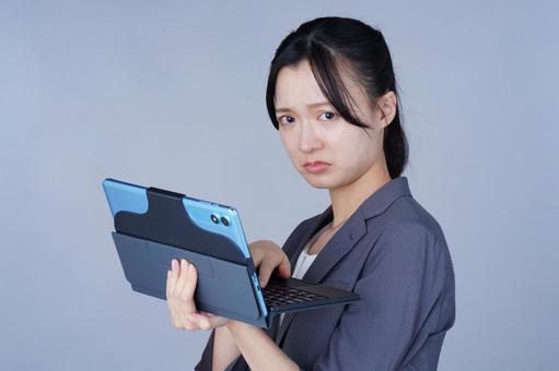 グレーの服の女性がタブレットを持つの写真