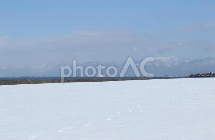  広場に積もった一面の雪と琵琶湖の水平線から見える雪山です 雪,琵琶湖,滋賀県の写真素材