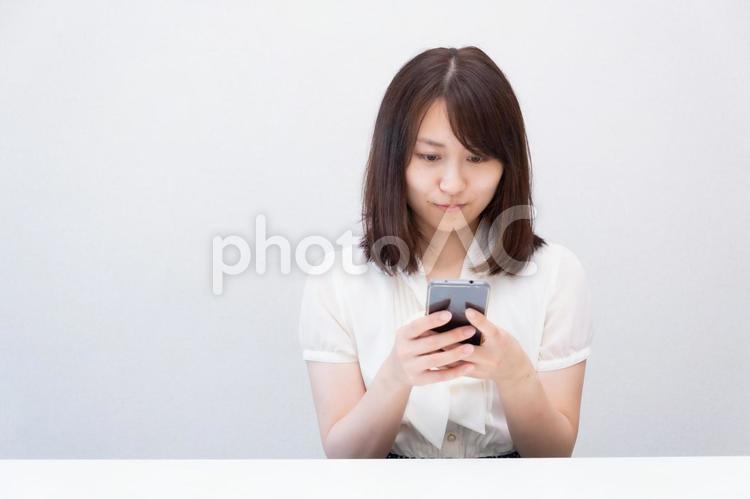 スマートフォンを両手で使っている女性 女性,スマートフォン,スマホの写真素材