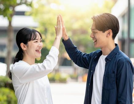 ハイタッチする若い男女 ハイタッチする若い男女の写真