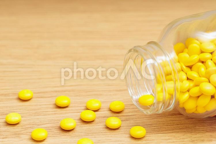 倒れた透明の瓶から黄色の錠剤が散らばる 薬,医薬品,内服薬の写真素材