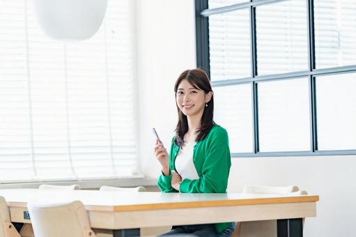 室内でスマートフォンを持ち微笑む女性 室内でスマートフォンを持ち微笑む女性 女性,スマートフォン,携帯電話の写真素材