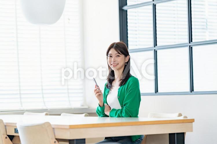 室内でスマートフォンを持ち微笑む女性 女性,スマートフォン,携帯電話の写真素材