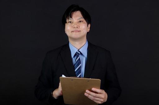 黒背景でメモを持つ男性 黒背景でメモを持つ男性 男性,黒背景,スーツの写真素材