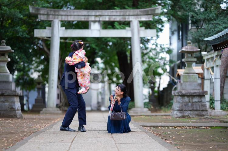 神社で着物姿の子どもを抱き上げる家族 七五三,お参り,七五三参りの写真素材