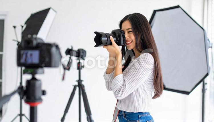 部屋で撮影する日本人女性フォトグラファー ミラーレス一眼レフカメラ,プロフェッショナル,スナップショットの写真素材