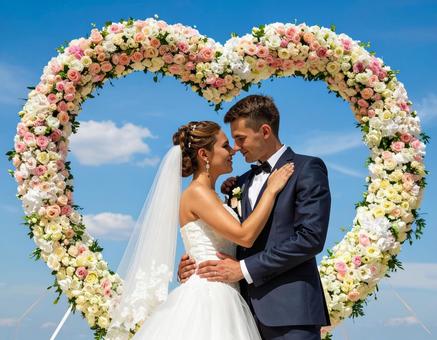 ハート形の花のアーチの前の新郎新婦 ハート形の花のアーチの前の新郎新婦の写真
