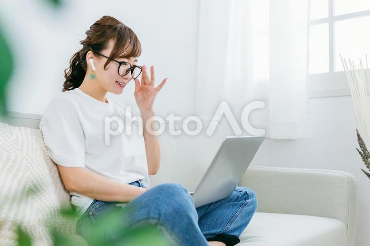イヤホンとパソコンを使うメガネの女性 メガネ,イヤホン,めがねの写真素材