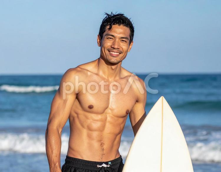 サーフィンをする筋肉質の日焼けした男性 海,サーフィン,男性の写真素材