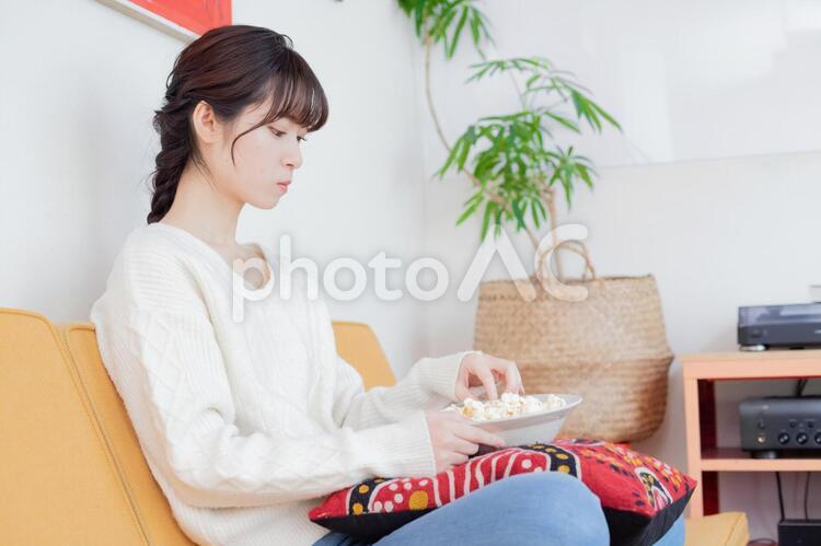ソファーでポップコーンを食べながらテレビを観る女性2 女性,日本人,テレビを観るの写真素材