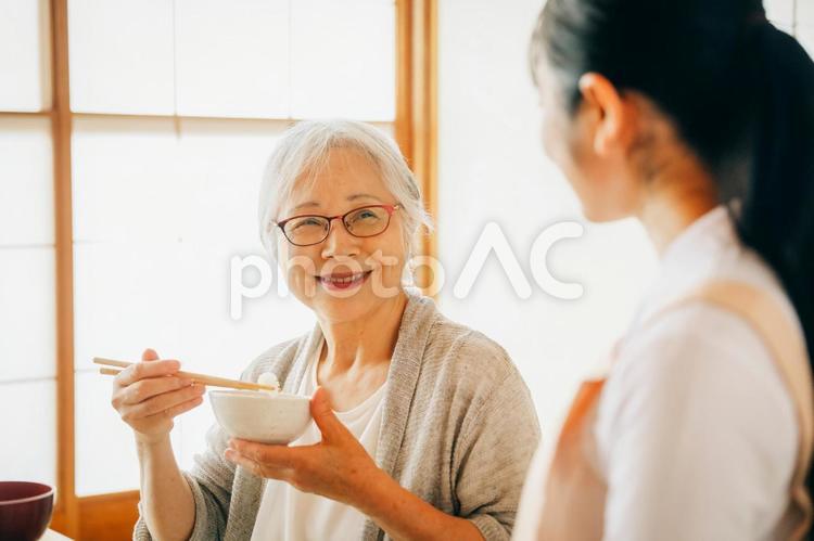 食事をする高齢者女性と女性スタッフ（笑顔） 高齢者,おばあちゃん,食事の写真素材