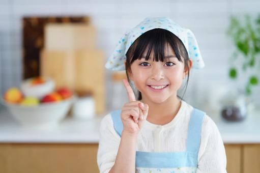 三角巾をつけた女の子のクッキングシーンの写真