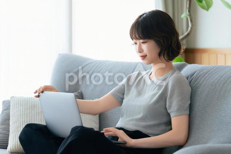 ソファに座ってパソコンを使う女性 女性,ソファ,パソコンの写真素材