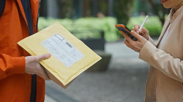 配達物を持っている配達員と受取サインをする女性 配達,デリバリー,配送の写真素材