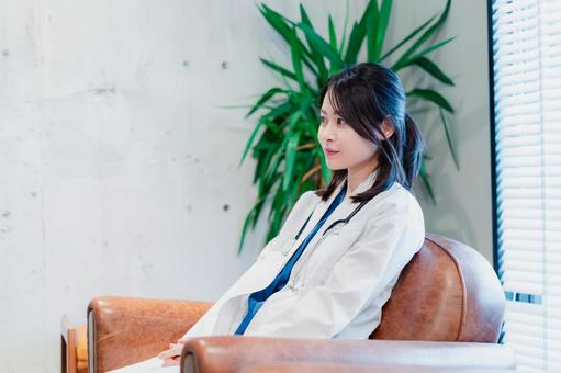 白衣で休憩をする女性の医師 白衣で休憩をする女性の医師 若い,ビジネスシーン,休憩室の写真素材