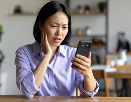 不安そうにスマホを見る女性の写真