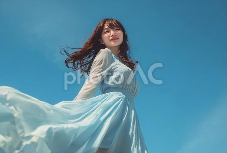 夢見るような表情の日本人女性と青空 女性,日本人女性,ドレスの写真素材