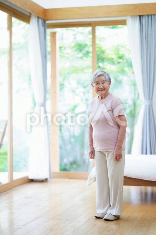 カメラ目線で立つベッド脇のおばあちゃん 女性,微笑む,笑顔の写真素材