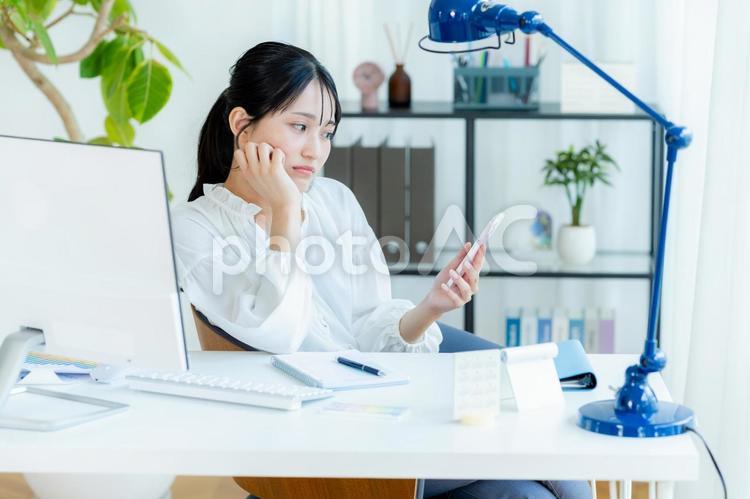 スマホを見ながら考えるビジネスウーマン スマホ,考える,悩むの写真素材