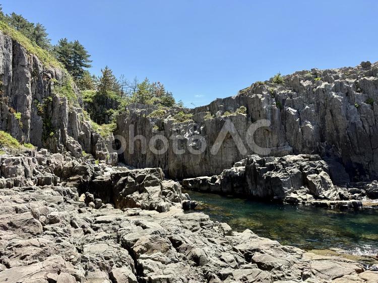 昼間の福井県の東尋坊 柱状節理,磯辺,水面の写真素材