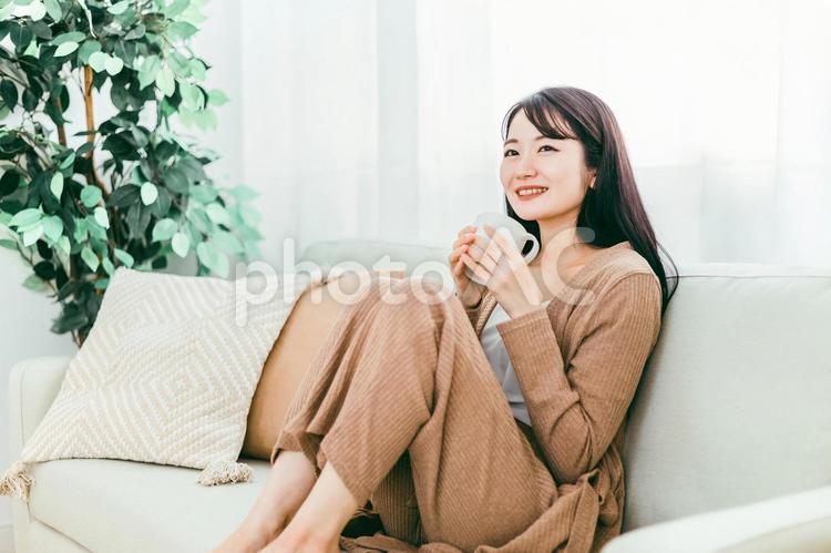 ホットドリンクを飲む女性（温活・ソファ） コーヒー,ソファ,女性の写真素材