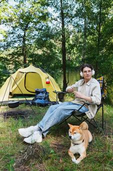 芝生で犬と椅子に座ってくつろぐ男性 男性,外国人,犬の写真素材