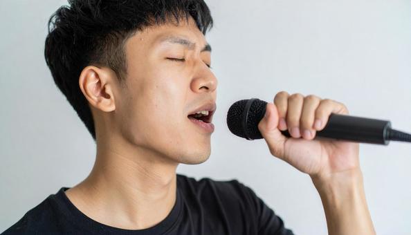 マイクを持って熱唱する日本人男性 マイクを持って熱唱する日本人男性の写真
