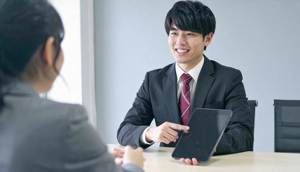タブレットを使って説明する男性営業マン タブレットを使って説明する男性営業マンの写真