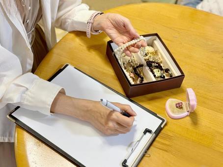アクセサリーを持って用紙に記入する女性 宝石,貴金属買取,出張買取の写真素材