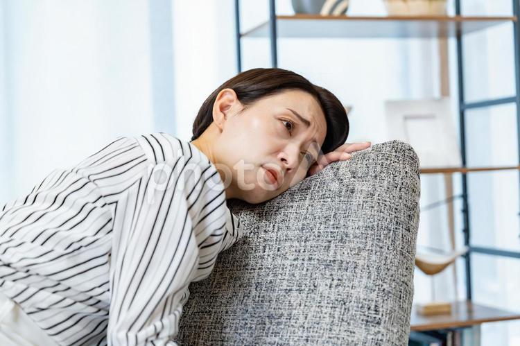 ソファに項垂れる女性 女性,ミドル,心配の写真素材
