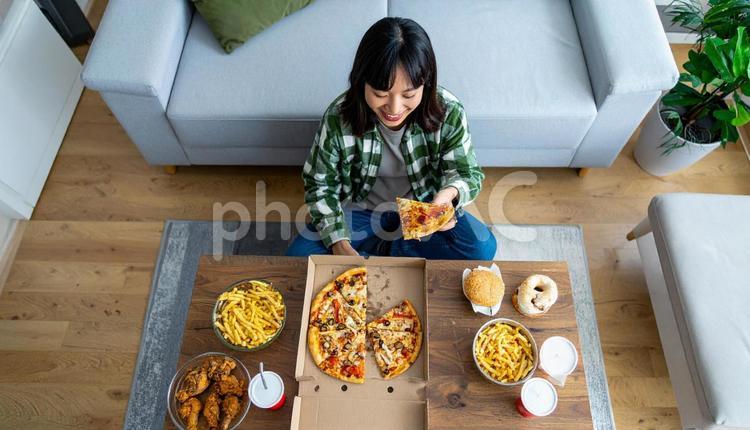 チートデイ　ジャンクフードを前に笑う女性 女性,ハンバーガー,ピザの写真素材