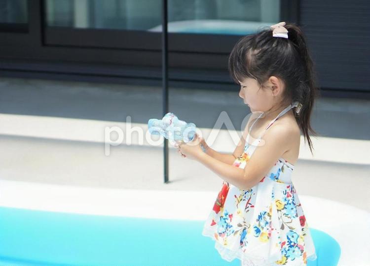 おうちプール　水鉄砲を持った水着姿の女の子 おうちプール,水着,子供の写真素材