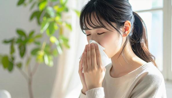 ティッシュで鼻をかむ日本人の若い女性の写真