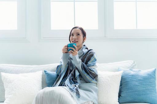 ソファでカップを持つ女性 リラックス,おうち時間,女性の写真素材